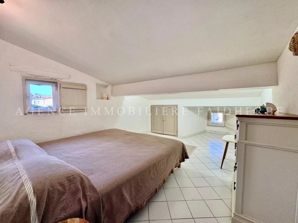 Chambre lumineuse avec un lit double et un espace de rangement sous le toit.