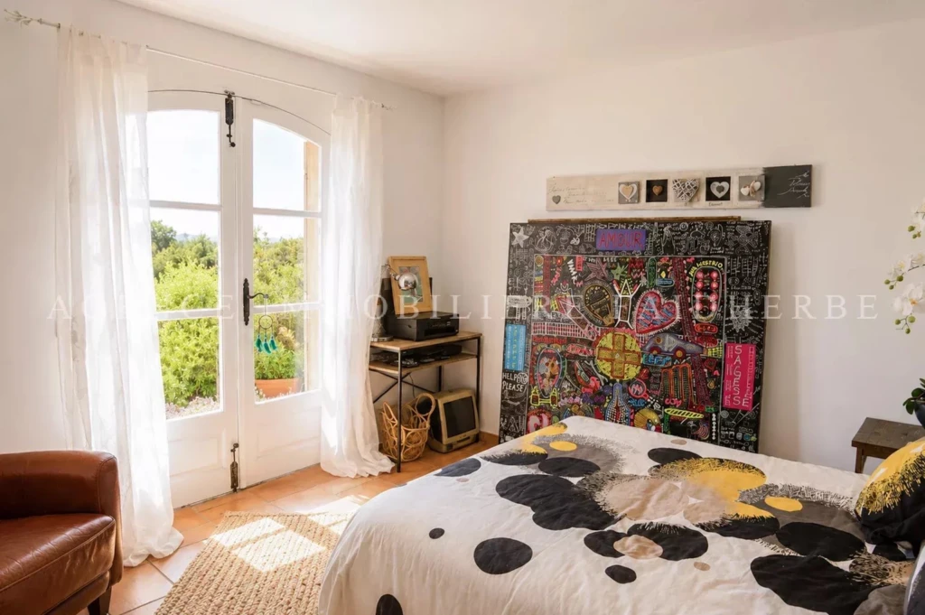 Chambre lumineuse avec un grand lit et décoration colorée, idéal pour un espace de repos confortable.