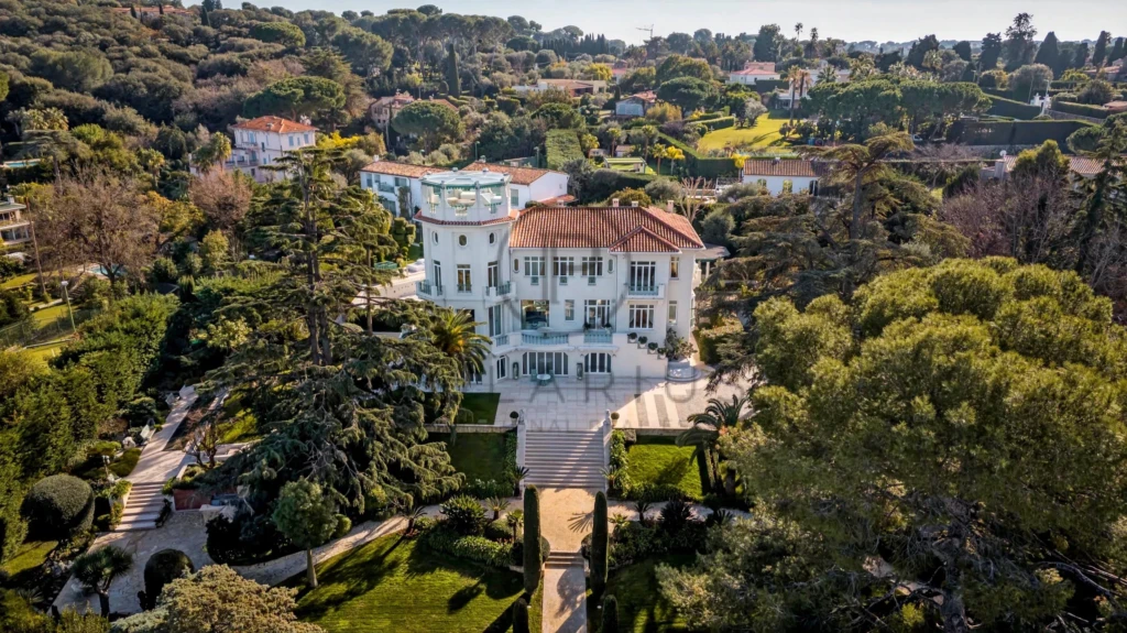 Domaine élégant entouré de jardins luxuriants et d'arbres, avec une grande villa au centre.