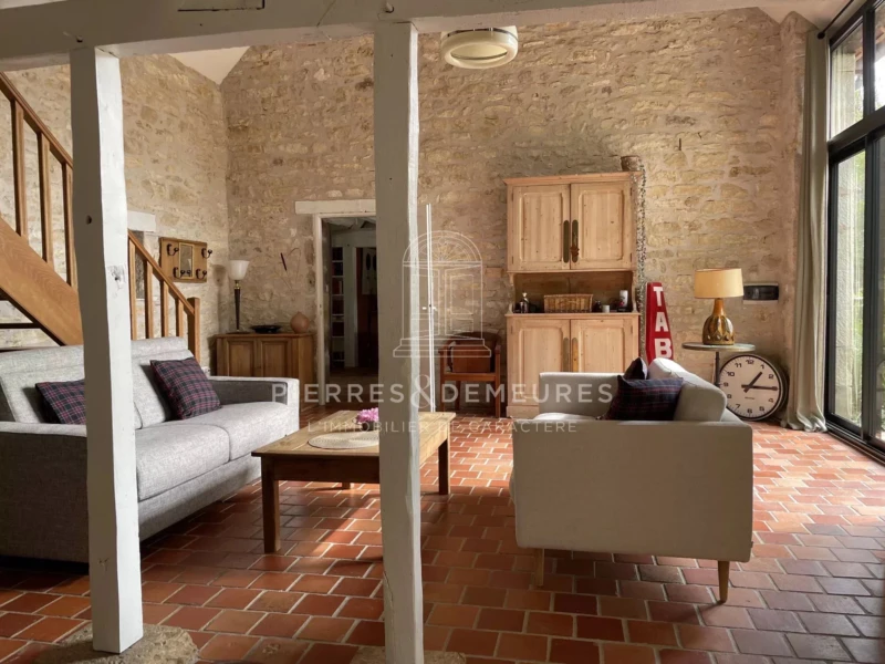 séjour lumineux, plafond cathédrale, murs en pierres apparentes, poutres en bois, grande baie vitrée en aluminium, luminosité, convivialité