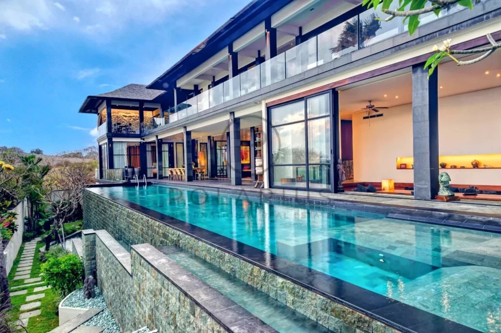 Une villa moderne avec piscine à débordement, entourée de verdure.