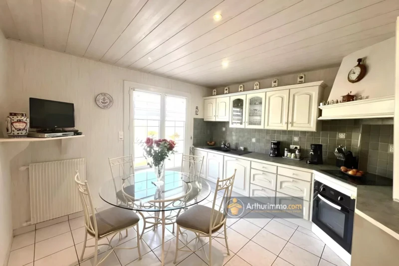 Cuisine lumineuse avec un mobilier blanc élégant et un coin repas convivial.