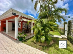 Une maison charmante avec un jardin tropical et une terrasse ombragée.