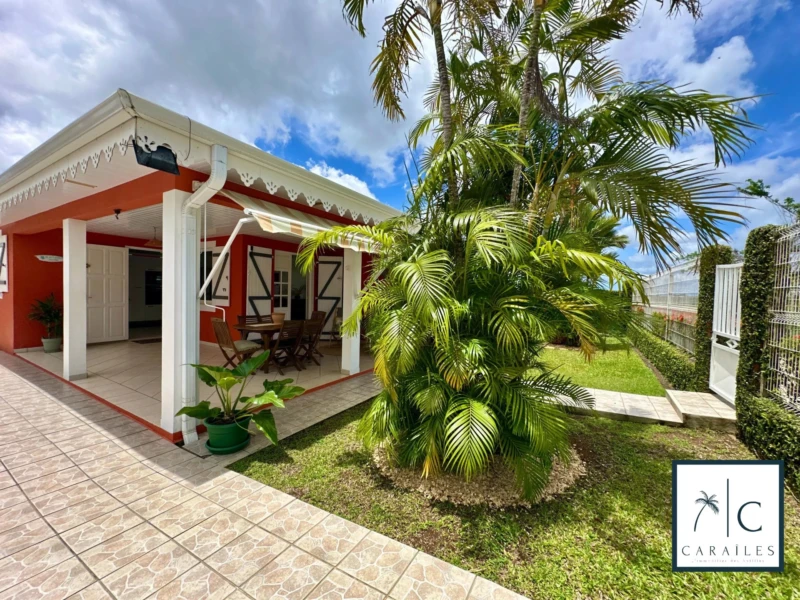 Une maison charmante avec un jardin tropical et une terrasse ombragée.