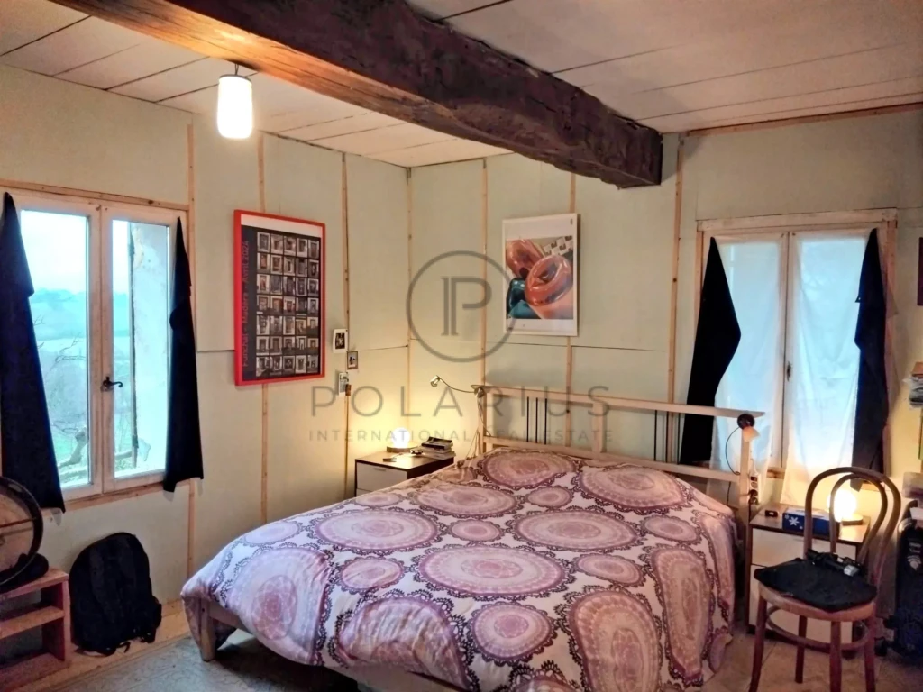 Chambre conviviale avec poutre en bois et fenêtres lumineuses.