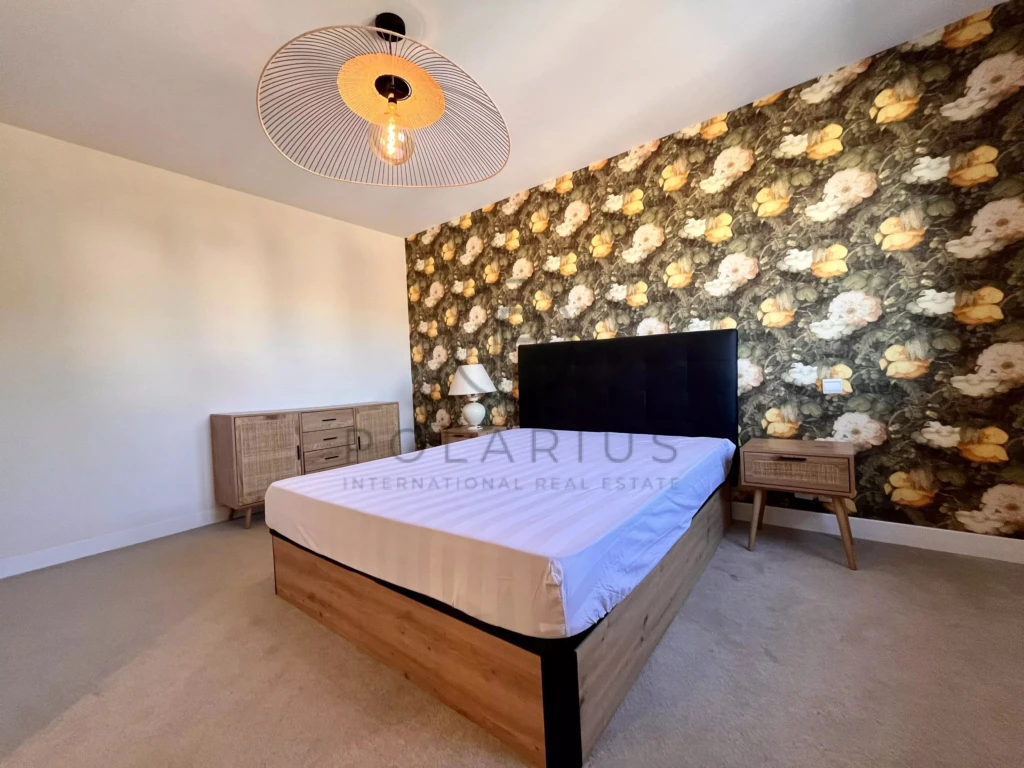 Chambre lumineuse avec un mur accent floral et un mobilier moderne.