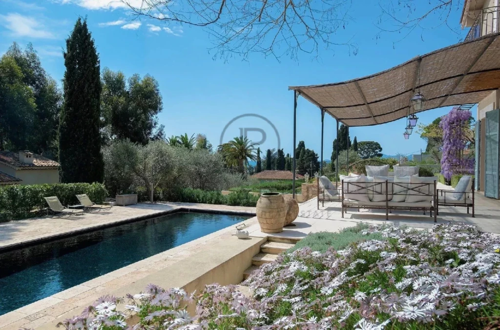 Terrasse avec piscine entourée de végétation luxuriante et de fleurs, offrant une vue sereine.