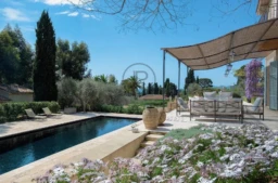 Terrasse avec piscine entourée de végétation luxuriante et de fleurs, offrant une vue sereine.