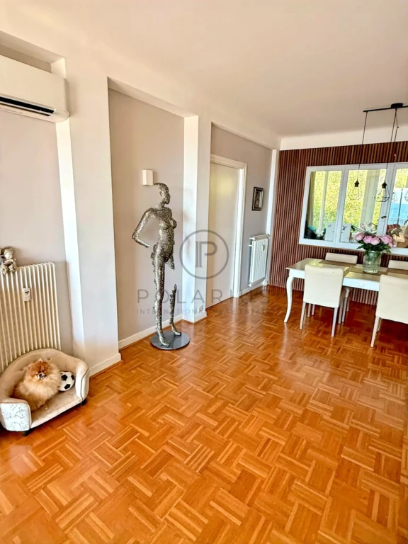Grand salon lumineux avec parquet en bois et espace pour accueillir famille et amis.