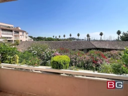 Grande terrasse avec vue sur un jardin fleuri et le port en arrière-plan.