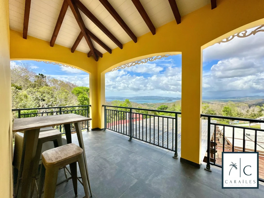 Balcon offrant une vue panoramique sur la nature et la mer dans une maison ensoleillée.