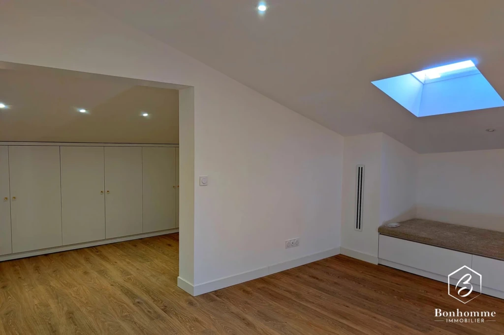 Une pièce spacieuse avec parquet, des placards intégrés et un puits de lumière.