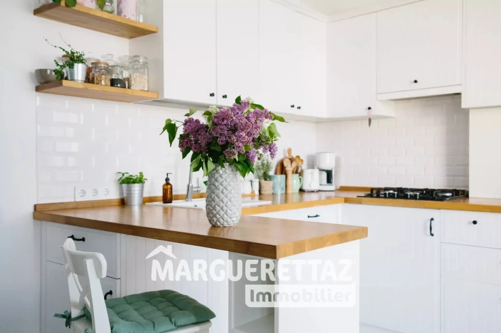 Modern white u-shaped kitchen in scandinavian style. Open shelves in the kitchen with plants and jars. Lilac bouquet in vase standing on wooden countertop