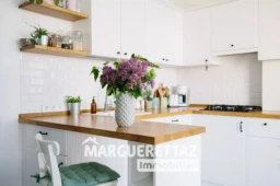 Modern white u-shaped kitchen in scandinavian style. Open shelves in the kitchen with plants and jars. Lilac bouquet in vase standing on wooden countertop