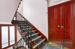 Escalier élégant avec garde-corps en métal et porte en bois massif dans l'entrée.
