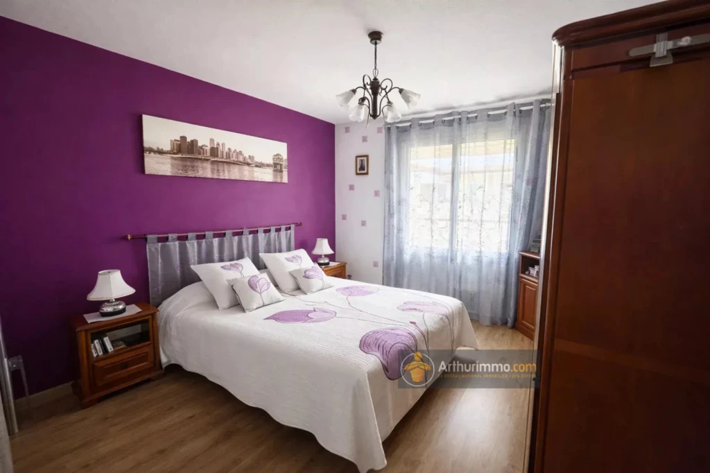 Chambre lumineuse avec mur violet et mobilier classique.