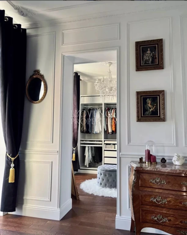 Une superbe perspective depuis la chambre vers un dressing spacieux, astucieusement dissimulé derrière des boiseries blanches raffinées.