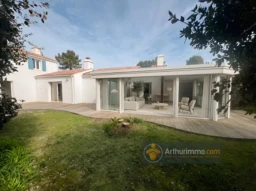 Belle maison moderne avec une véranda en verre et un grand jardin.
