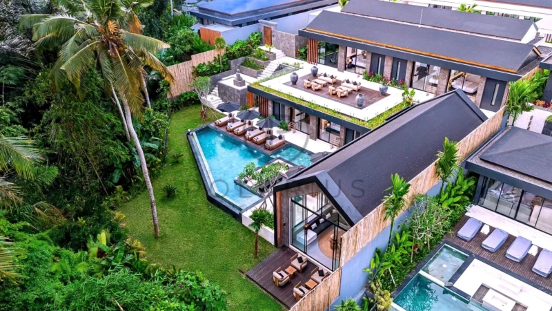 Une villa moderne entourée de végétation luxuriante, avec piscine et espaces de détente extérieurs.