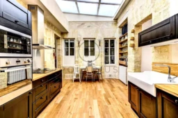 Cuisine lumineuse avec murs en pierre apparente et sol en bois chaleureux.