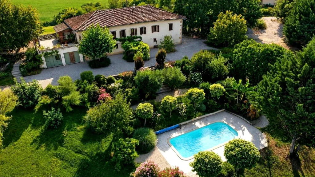 Belle propriété avec une grande maison, une piscine et un jardin luxuriant.