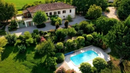 Belle propriété avec une grande maison, une piscine et un jardin luxuriant.