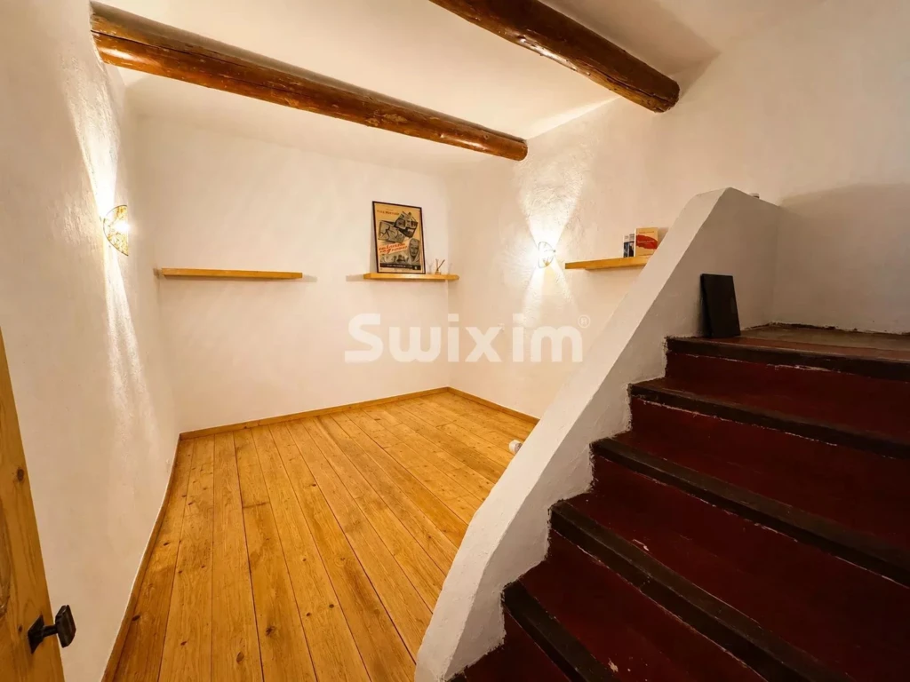 Pièce cosy avec un sol en bois et des murs blancs, idéal pour la détente.