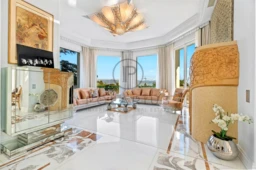 Un salon élégant avec des sofas beige, de grandes fenêtres offrant une vue panoramique et une décoration raffinée.