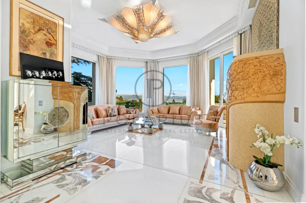 Un salon élégant avec des sofas beige, de grandes fenêtres offrant une vue panoramique et une décoration raffinée.