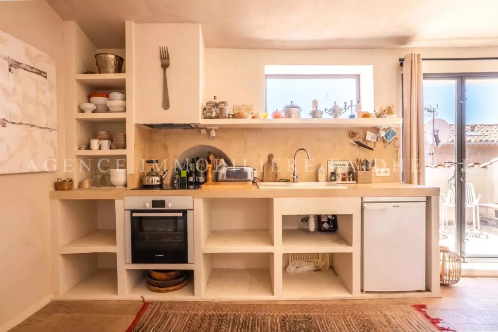 Cuisine lumineuse avec de nombreux rangements et accès à un balcon.