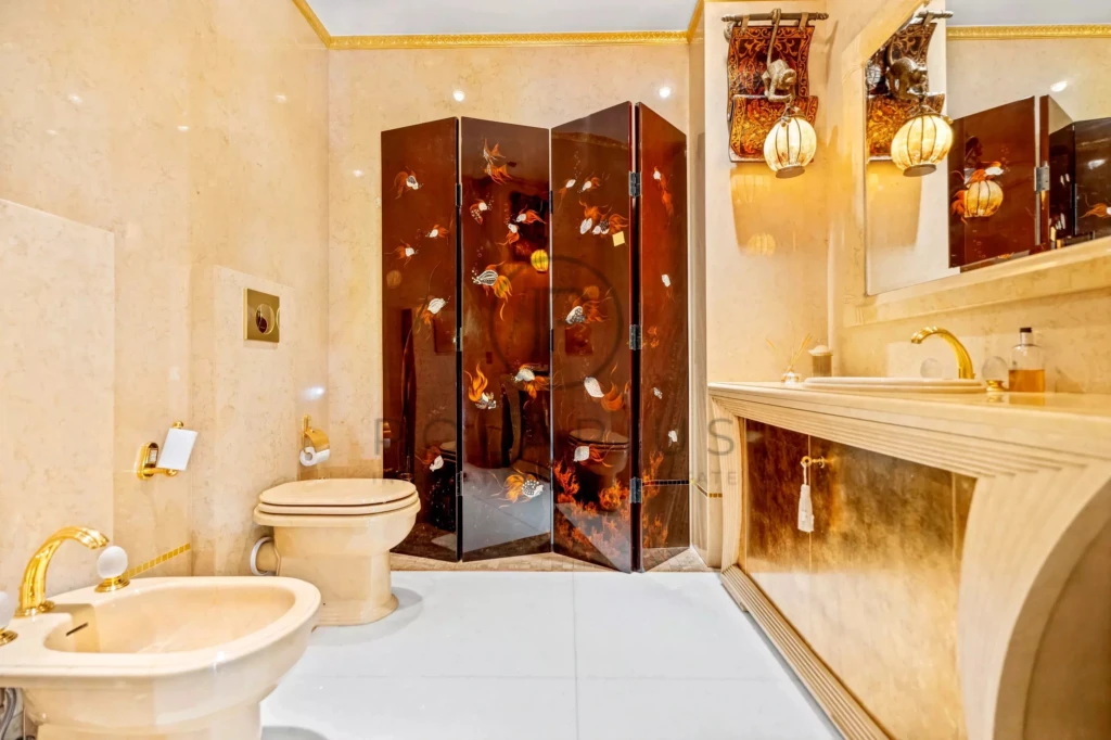 Cette image montre une salle de bains luxueuse avec des finitions dorées et un décor élégant.