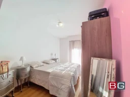 Une chambre lumineuse avec un lit double, armoire, table de chevet et miroir.