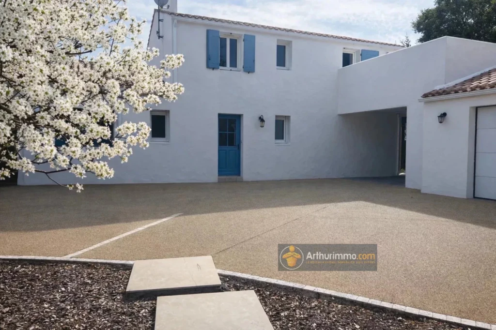 jolie maison blanche avec cour spacieux et arbre en fleurs près de la propriété.