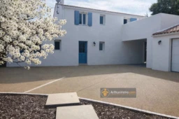 jolie maison blanche avec cour spacieux et arbre en fleurs près de la propriété.