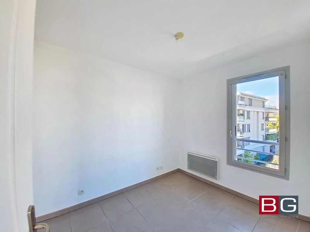 Petite pièce lumineuse avec un mur blanc, une fenêtre et un radiateur.