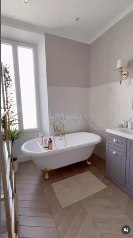 Un véritable espace de détente comprenant une baignoire îlot rétro à pieds de lion, une faïence effet marbre et une belle luminosité naturelle.