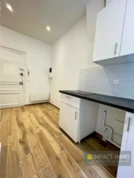 Cuisine moderne et lumineuse avec un sol en bois et des rangements blancs.