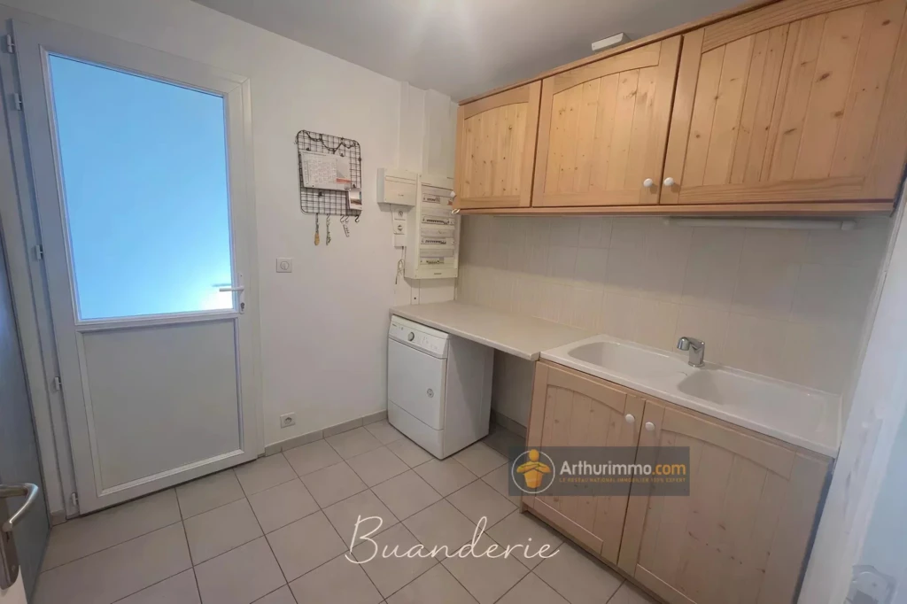 Buanderie pratique avec espace pour la machine à laver et rangement mural.