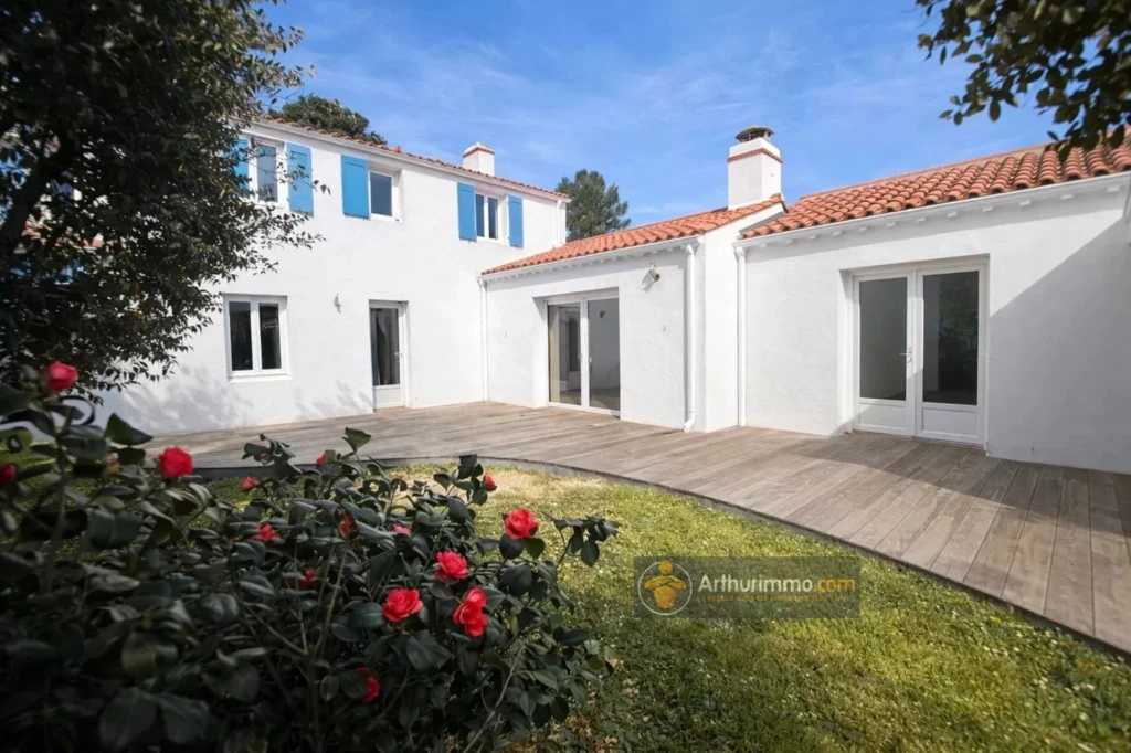 Belle maison avec un jardin verdoyant et une terrasse ensoleillée.
