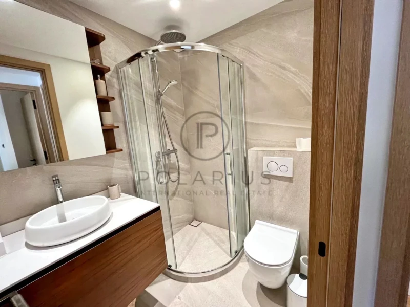 Une salle de bain moderne avec une douche vitrée, un lavabo sur un meuble en bois et des toilettes blanches.