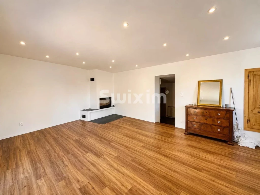 Grand salon lumineux avec cheminée et parquet en bois naturel.