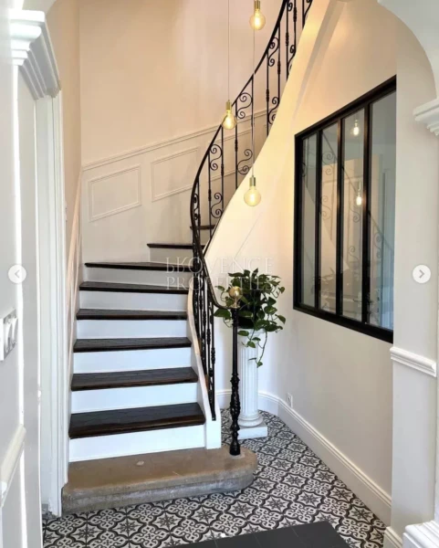 Une transition élégante sur le palier, optimisant la lumière naturelle grâce à une verrière de style atelier.