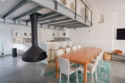 Salle à manger ouverte sur la cuisine moderne avec un poêle à bois suspendu.
