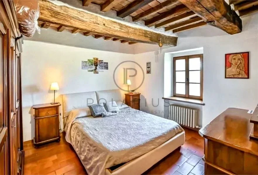 Chambre chaleureuse avec poutres apparentes et lumière naturelle.