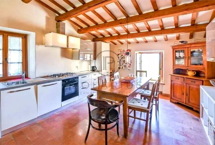 Cuisine chaleureuse avec poutres apparentes et espace convivial.