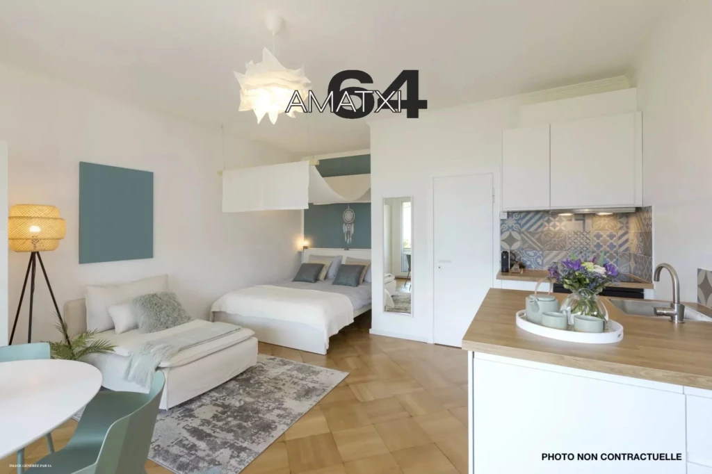General view of a stylish modern studio apartment. There is a small kitchen with a wooden counter, a double bed and a single bed, and a table with chairs. No one inside