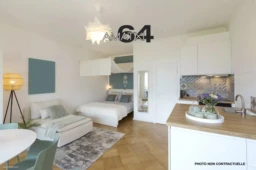 General view of a stylish modern studio apartment. There is a small kitchen with a wooden counter, a double bed and a single bed, and a table with chairs. No one inside