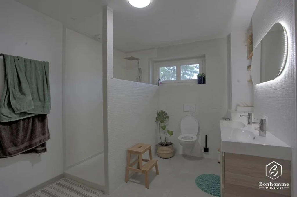 Salle de bain lumineuse avec toilettes, lavabo et espace de rangement.