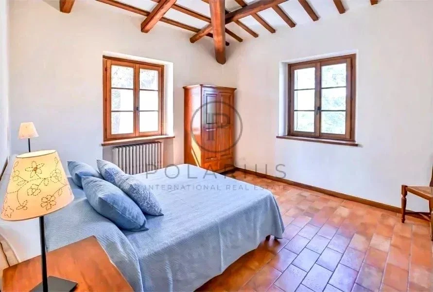 Chambre lumineuse avec poutres en bois et fenêtres spacieuces, idéale pour un séjour agréable.