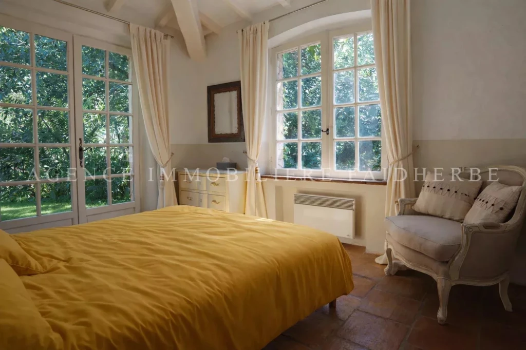 Chambre lumineuse avec vue sur le jardin, dotée d'un lit confortable et d'un mobilier élégant.